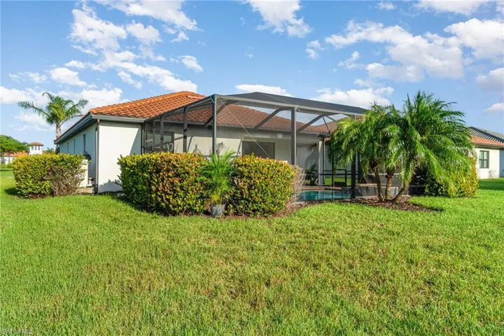 Rear view of property featuring a tile roof, a yard, stucco siding, and glass enclosure