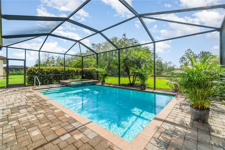View of pool with a patio area, a pool with connected hot tub, a lawn, and glass enclosure