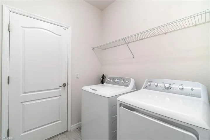 Laundry area featuring washing machine and clothes dryer and baseboards
