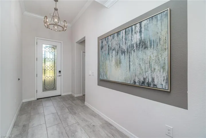 Entrance foyer with ornamental molding and a chandelier