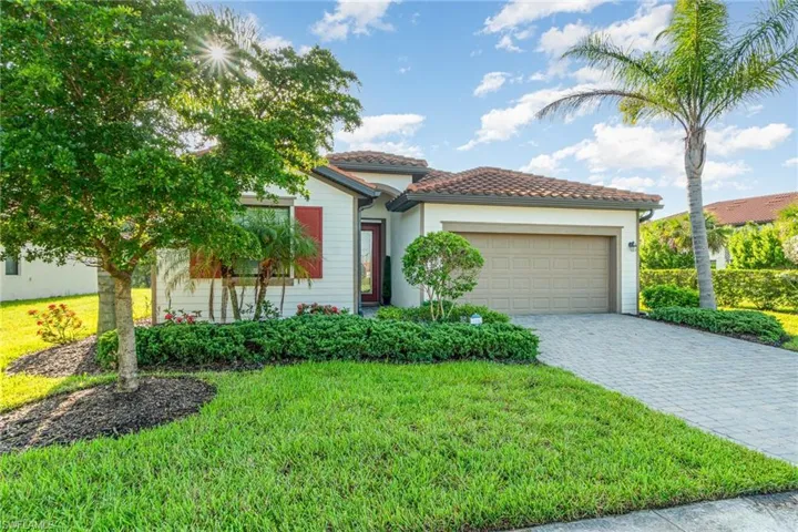 Mediterranean / spanish-style home with an attached garage, a front yard, decorative driveway, and stucco siding