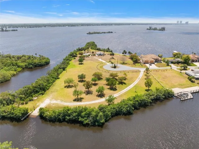 Expansive waterfront property featuring a boat ramp, private dock, multiple mature trees, and a circular driveway