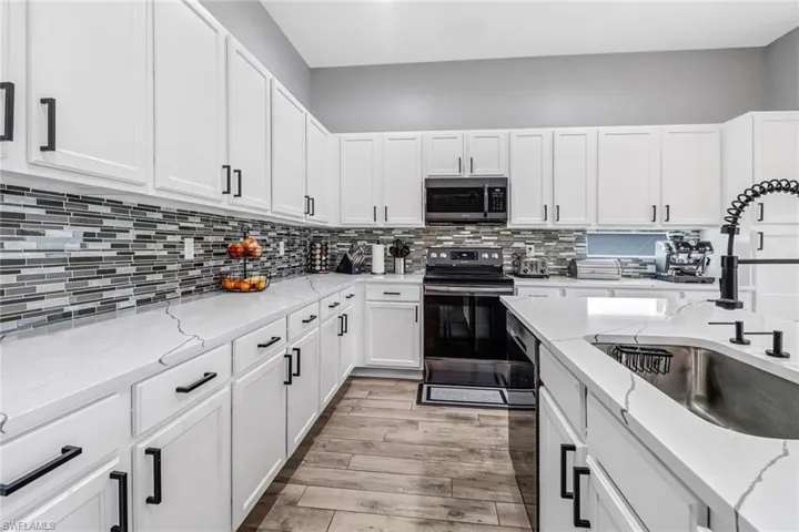 Kitchen featuring light hardwood / wood-style flooring, tasteful backsplash, electric stove, and light stone counters