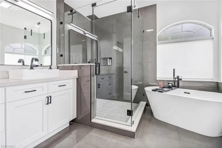 Bathroom with tile patterned floors, a wealth of natural light, and separate shower and tub