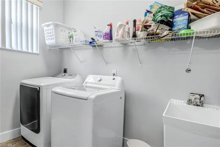 Laundry room with sink, independent washer and dryer, and hardwood / wood-style floors