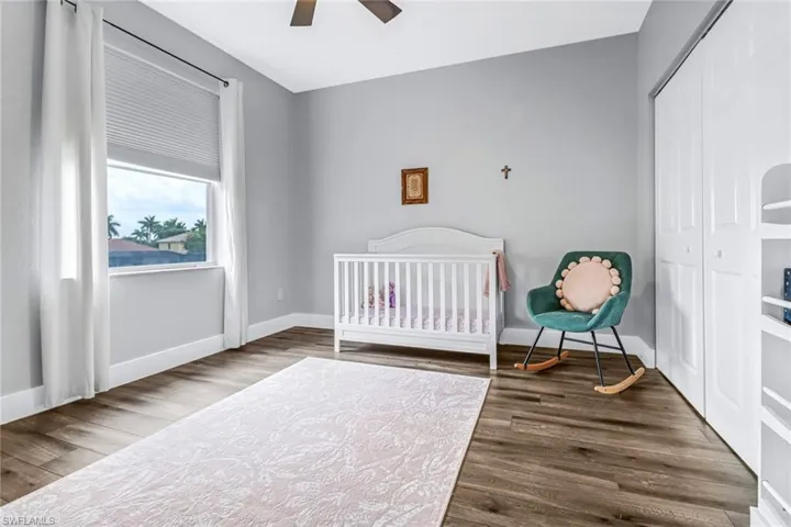 Bedroom with ceiling fan, a closet, wood-type flooring, and a nursery area