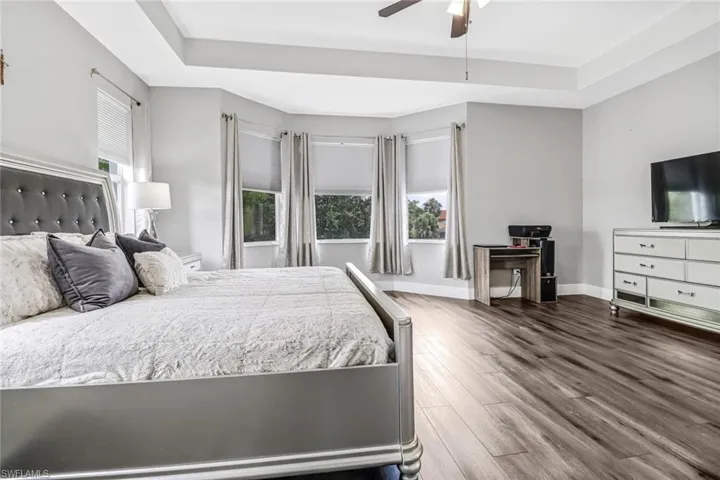 Bedroom featuring ceiling fan, a tray ceiling, and hardwood / wood-style flooring