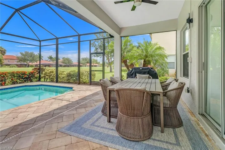 View of swimming pool with a patio, ceiling fan, and glass enclosure