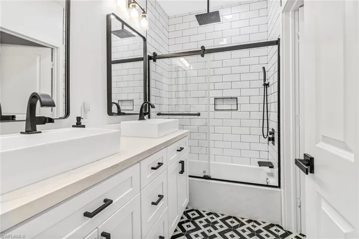 Bathroom featuring tile patterned floors, combined bath / shower with glass door, and double sink vanity