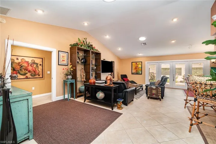 Tiled living room with french doors and lofted ceiling