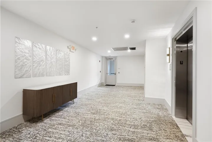 Hall with light carpet and elevator