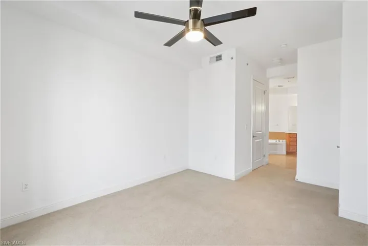 Empty room with ceiling fan and light colored carpet