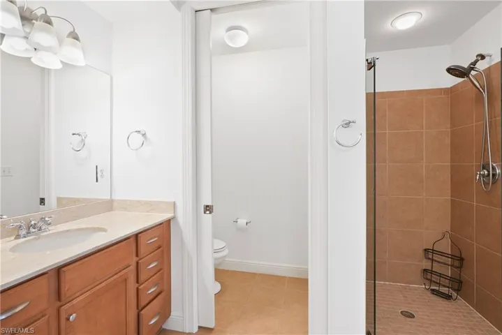 Bathroom with vanity, toilet, tiled shower, and tile patterned flooring