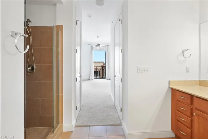 Bathroom featuring vanity, walk in shower, tile patterned floors, and ceiling fan