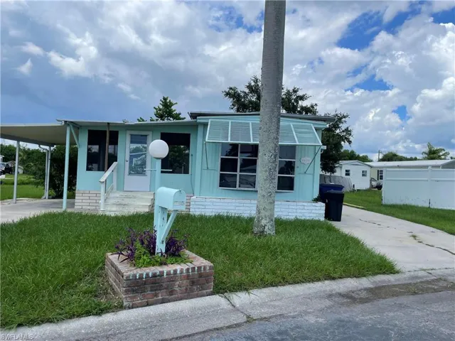 Manufactured / mobile home featuring a carport and a front yard