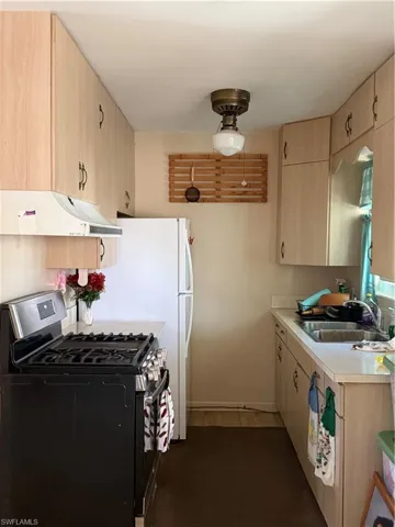 Kitchen with stove, light wood finish cabinetry, light countertops, and ventilation hood