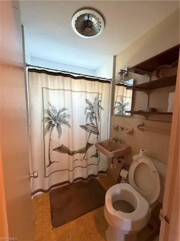Bathroom with a shower curtain, tile walls, and light floors