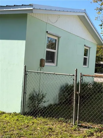 View of side of home with a gate and stucco siding