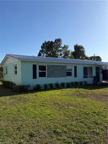 View of front facade with a front yard, a metal roof, and stucco siding