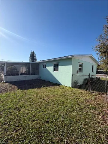 Back of house with a sunroom, a gate, and stucco siding