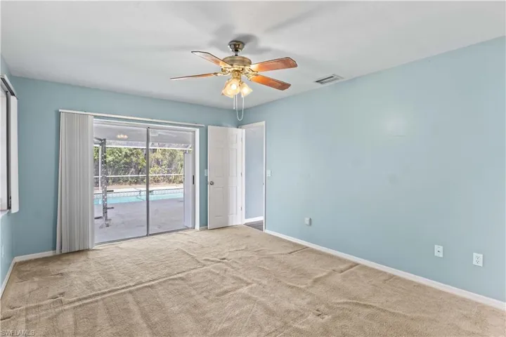 Carpeted spare room with ceiling fan, visible vents, and baseboards