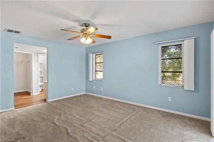 Unfurnished room featuring a healthy amount of sunlight, carpet floors, baseboards, and visible vents
