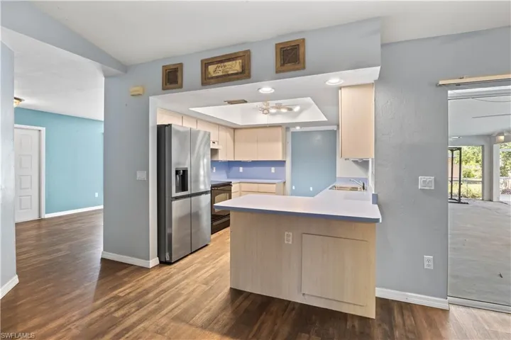 Kitchen with baseboards, a peninsula, stainless steel fridge with ice dispenser, and wood finished floors