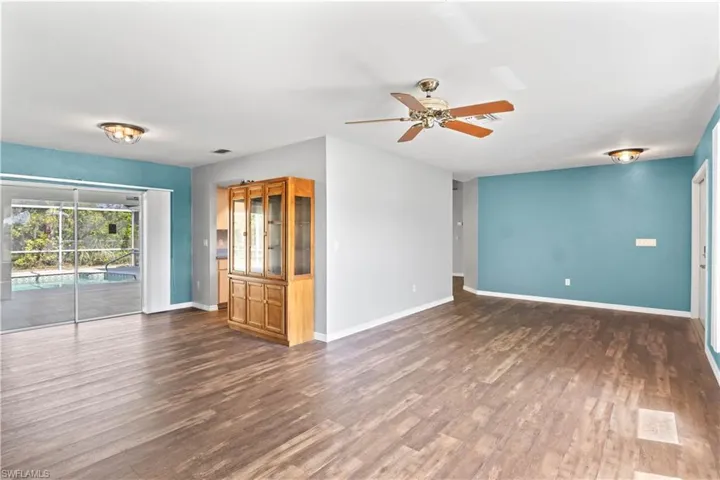 Unfurnished living room featuring a ceiling fan, visible vents, baseboards, and wood finished floors