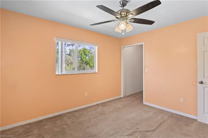 Unfurnished bedroom featuring light carpet, a ceiling fan, and baseboards