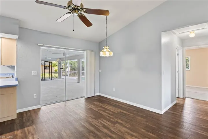 Empty room with lofted ceiling, ceiling fan, baseboards, and dark wood-type flooring