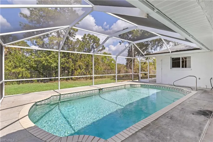 Pool featuring a lanai, a patio area, fence, and a lawn