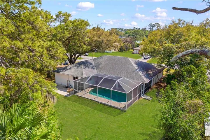 View from above of property with a pool area and a tree filled landscape