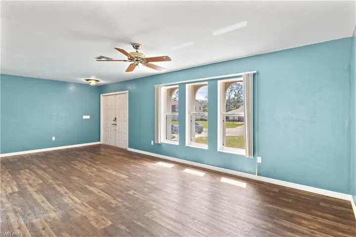 Empty room with a ceiling fan, baseboards, and wood finished floors