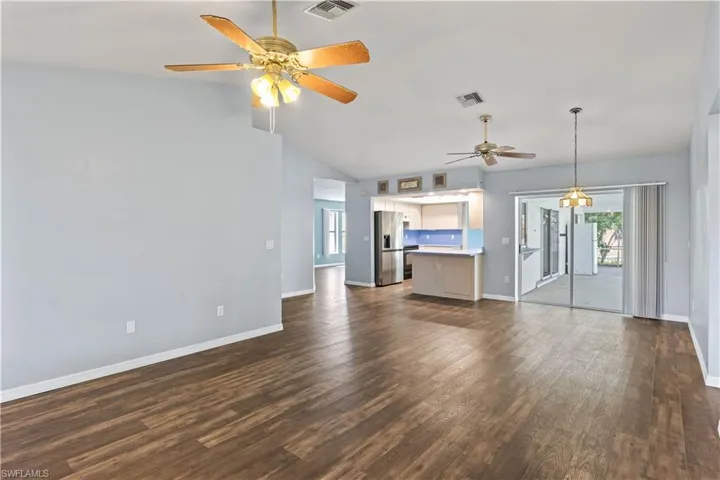 Unfurnished living room featuring dark wood finished floors, visible vents, and baseboards