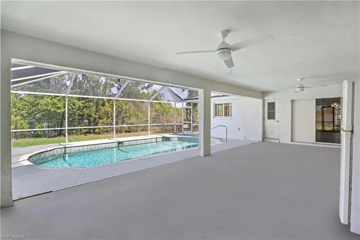 Swimming pool featuring ceiling fan, a patio area, and glass enclosure