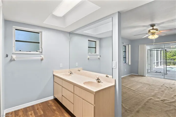 Full bathroom with double vanity, a ceiling fan, baseboards, and a sink
