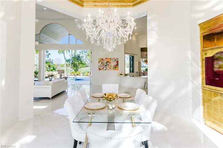 Dining area featuring light tile patterned flooring, ornamental molding, a towering ceiling, and an inviting chandelier