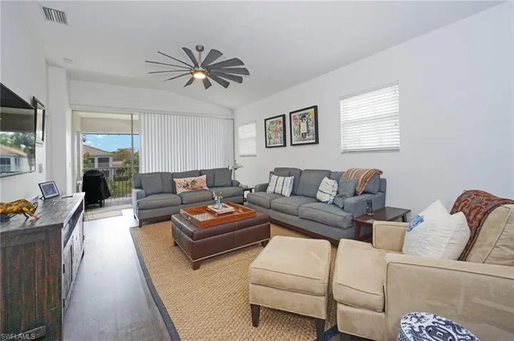 Living area featuring lofted ceiling, visible vents, wood finished floors, and a ceiling fan