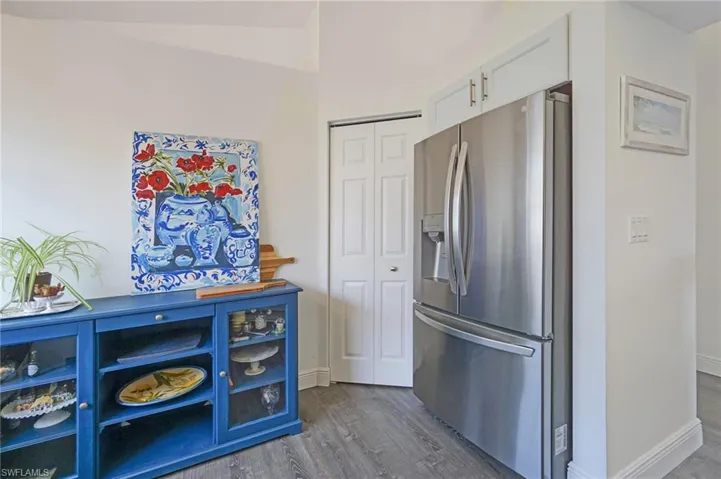 Kitchen featuring baseboards, dark wood-style flooring, white cabinets, and stainless steel fridge