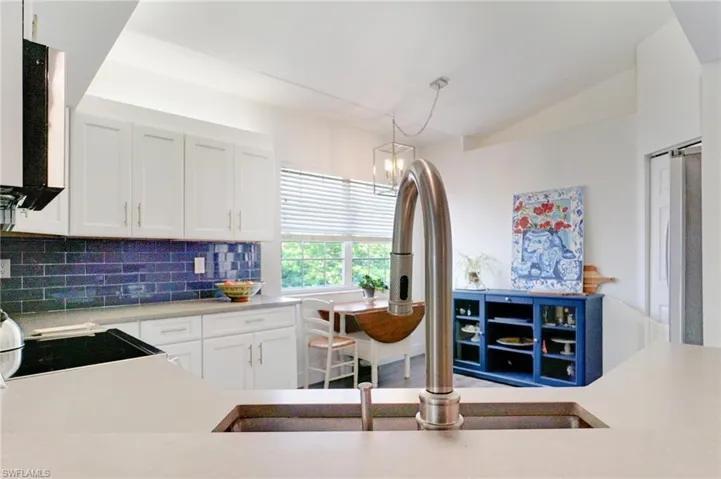Kitchen featuring light countertops, decorative light fixtures, range, backsplash, and white cabinets
