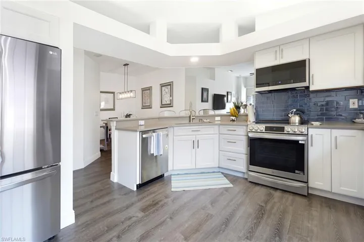 Kitchen featuring white cabinetry, decorative backsplash, appliances with stainless steel finishes, and a peninsula