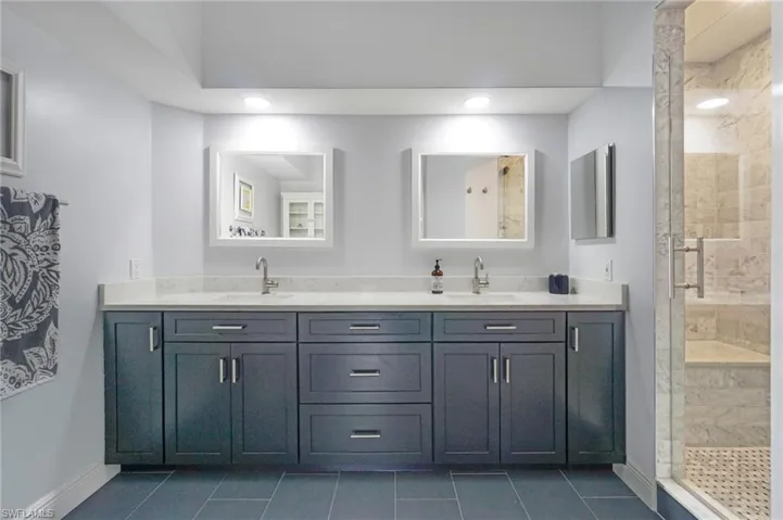 Bathroom with a shower stall, tile patterned floors, double vanity, and a sink