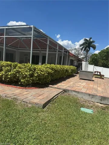 Rear view of house featuring a patio, fence, a yard, and glass enclosure