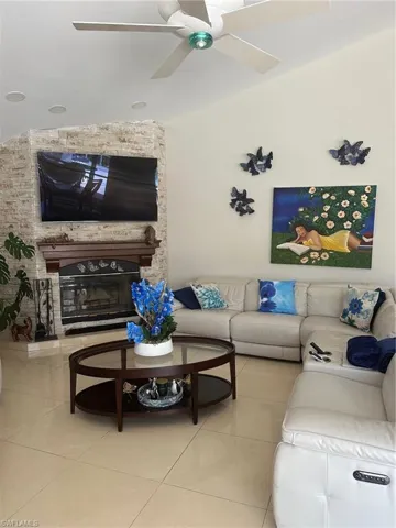 Tiled living room featuring a ceiling fan and vaulted ceiling