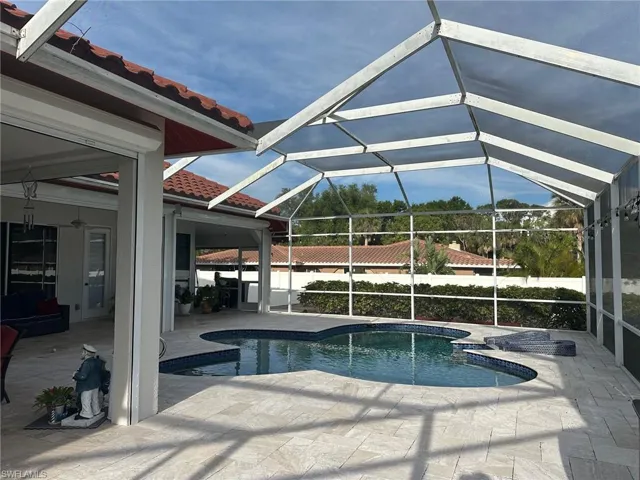 View of swimming pool with glass enclosure, a patio area, and a fenced in pool