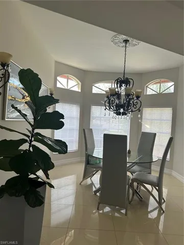 Dining space featuring light tile patterned flooring, a notable chandelier, and baseboards