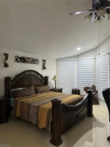 Tiled bedroom with a ceiling fan, lofted ceiling, and recessed lighting