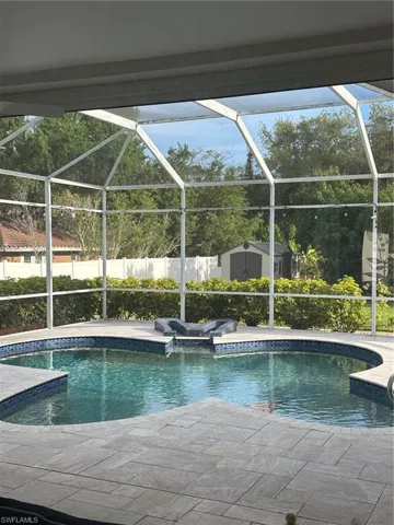 View of pool featuring an outbuilding, fence, a storage unit, a fenced in pool, and a patio area