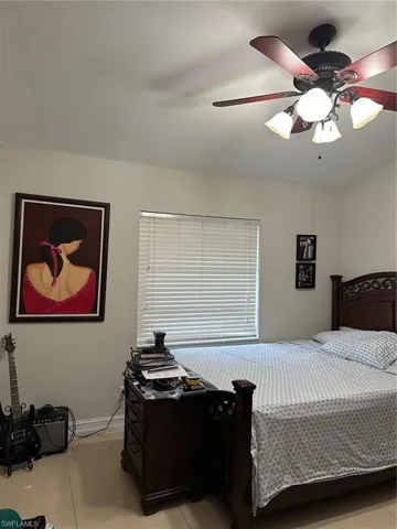 Bedroom with light tile patterned flooring, baseboards, and ceiling fan