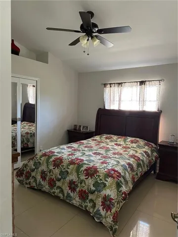 Tiled bedroom with a closet, ceiling fan, and vaulted ceiling